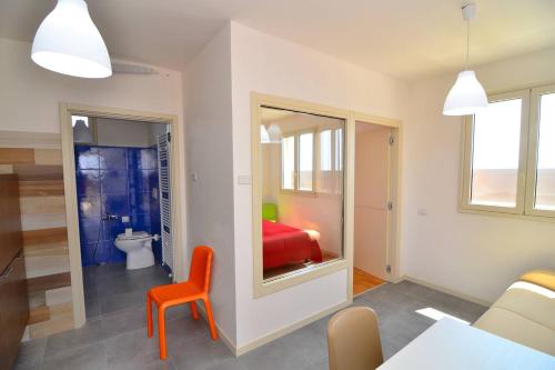 a living room with a red chair and a bathroom at Boomerang Village in Torre Colimena