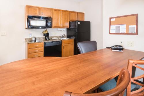 a kitchen with a wooden table and a black refrigerator at Candlewood Suites Wake Forest-Raleigh Area by IHG in Wake Forest