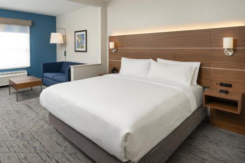a bedroom with a large bed and a blue chair at Holiday Inn Express & Suites Orlando International Airport by IHG in Orlando