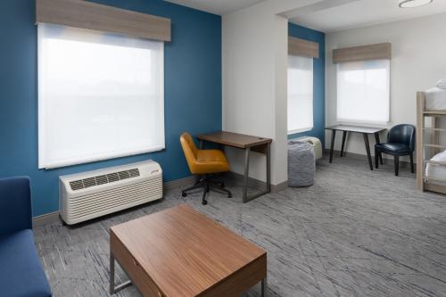 a room with a bed and a desk and chairs at Holiday Inn Express & Suites Orlando International Airport by IHG in Orlando