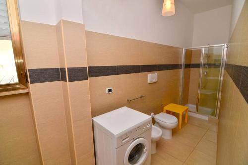 a bathroom with a toilet and a washing machine at Boomerang Village in Torre Colimena