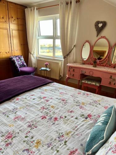 a bedroom with a bed and a dresser and mirror at The Burren Coach House in Bealaclugga