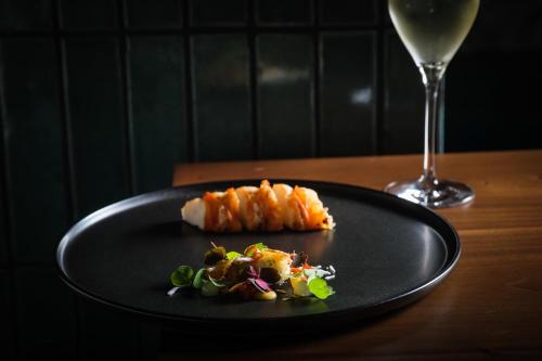 a black plate with food and a glass of wine at Hotel Indigo Grand Cayman by IHG in Grand Cayman