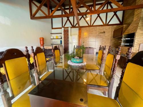 a dining room with a glass table and yellow chairs at Melhor Casa de Curitiba pra vc in Curitiba