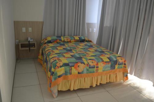 1 dormitorio con 1 cama con colcha colorida en Annamar Hotel, en João Pessoa