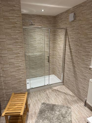 ein Bad mit einer Dusche, einer Bank und einem Tisch in der Unterkunft Fadó & Tide Apartments in Filey