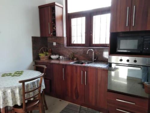 a kitchen with wooden cabinets and a table and a microwave at Green Court Villa in Talawatugoda
