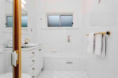 ein weißes Badezimmer mit Badewanne und Waschbecken in der Unterkunft Oasis - Luxe living, with pool - walk to cafes in Rose Park