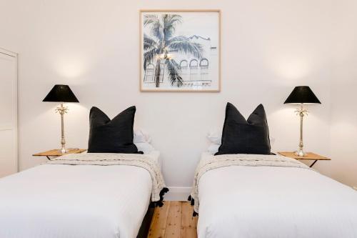 2 Betten in einem Zimmer mit weißen Wänden und schwarzen Kissen in der Unterkunft Oasis - Luxe living, with pool - walk to cafes in Rose Park