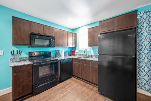 a kitchen with black appliances and wooden cabinets at Chic Comfort Near Houston Hotspots in Houston