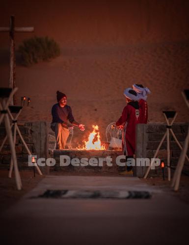 two people standing around a fire on the beach at Eco Desert Camp in Merzouga