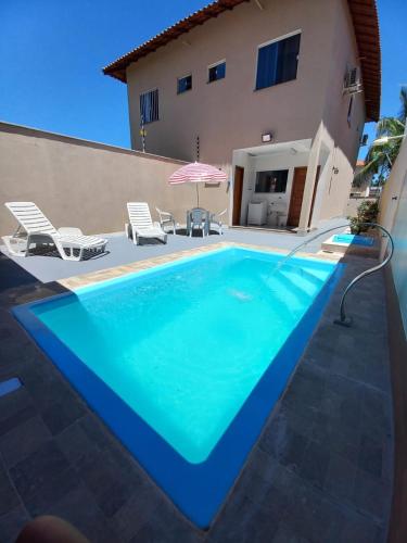 a blue swimming pool in front of a house at Casa Climatizada com Piscina em Jacaraipe in Serra