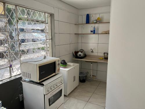 a kitchen with a microwave on top of a stove at Casa para 9 pessoas perto da Dom Pedro 2 in Porto Alegre