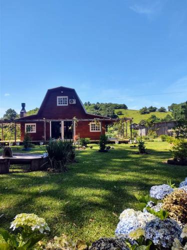 a red house with a green yard with flowers at Pousada Rancho do Lago in Osório