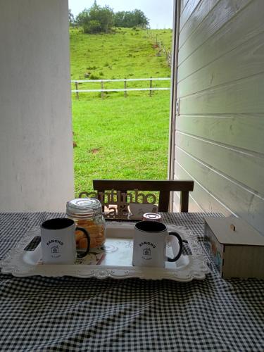 a tray with two coffee mugs on a table near a window at Pousada Rancho do Lago in Osório