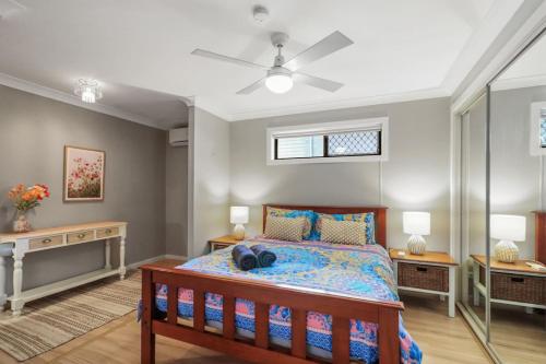 a bedroom with a bed and a ceiling fan at Mermaids at the Bay in Toowoon Bay
