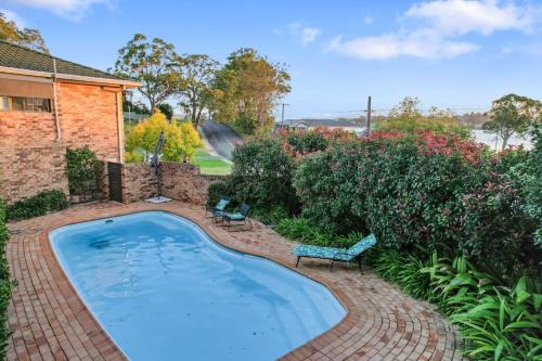 a swimming pool in a brick yard with two chairs at Sealand Retreat in Fishing Point