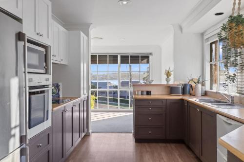 a kitchen with brown cabinets and a large window at Sealand Retreat in Fishing Point