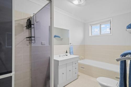 a white bathroom with a sink and a shower at Budge near the Beach in Budgewoi