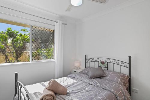 a white bedroom with a bed and a window at Waterside Escape in Dora Creek