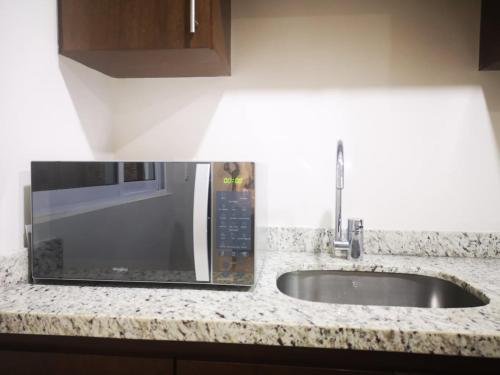 a kitchen counter with a microwave and a sink at Casa Soly in Mazatlán