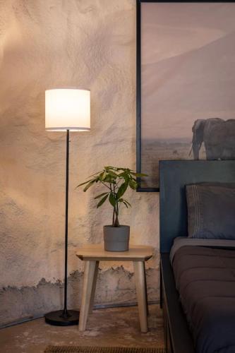 a lamp with a plant on a table next to a bed at The Caves at Moab - At Private Riverside Ranch in Moab