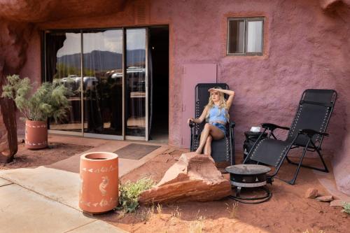 a woman sitting on a chair in front of a building at The Caves at Moab - At Private Riverside Ranch in Moab