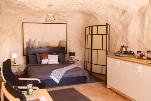a bedroom with a bed and a table and a kitchen at The Caves at Moab - At Private Riverside Ranch in Moab