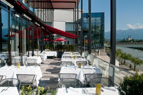 a row of white tables and chairs on a building at voco Villach by IHG in Villach