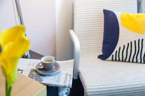 a cup of coffee sitting on a table next to a bed at voco Villach by IHG in Villach