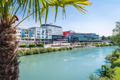 a view of a river with buildings in the background at voco Villach by IHG in Villach
