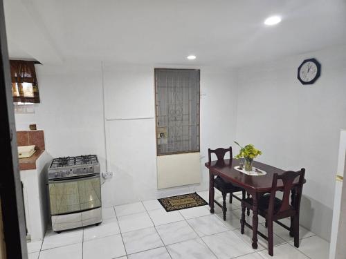 a kitchen with a table and a clock on the wall at LADVILLE Apartment near Kingstown #1 in Kingstown