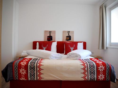 a bed with red and white blankets and pillows at Bergblick in Werfenweng