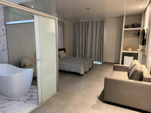 a bathroom with a bath tub and a bedroom at AR Pousada in Santa Bárbara