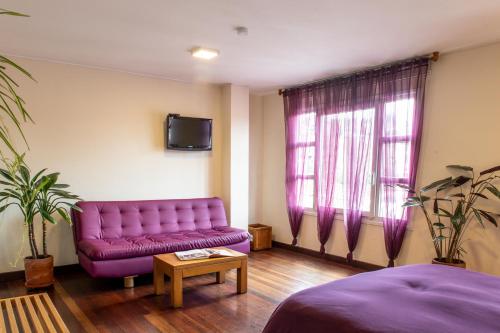 a living room with a purple couch and a tv at Hotel Casa Deco in Bogotá