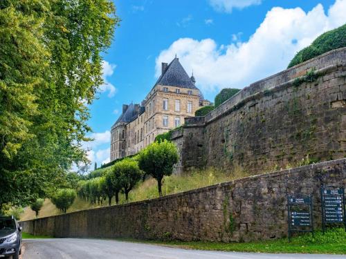 a castle on a hill next to a stone wall at Charming Holiday Home with Private Pool in Hautefort