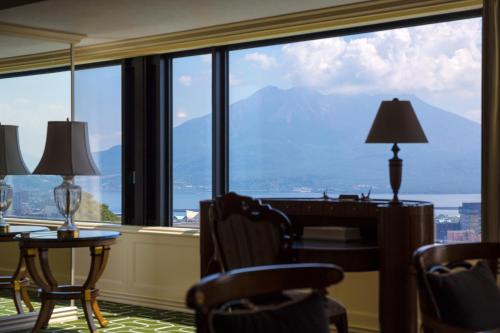 a room with a large window with a view of the mountains at SHIROYAMA HOTEL kagoshima in Kagoshima