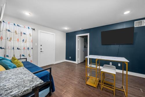 a living room with a blue wall with a flat screen tv at Cozy Sanctuary Near MedCenter, UH and NRG in Houston
