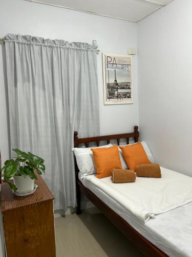 a bedroom with a bed with white sheets and orange pillows at Casa Residence by Baluyut in Concepcion