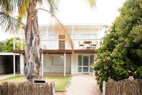 a house with a palm tree in front of it at Rockpool at Maslins Beach in Maslin Beach