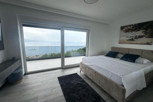 a bedroom with a large bed and a large window at Family friendly house with a swimming pool Opatija - 23833 in Matulji