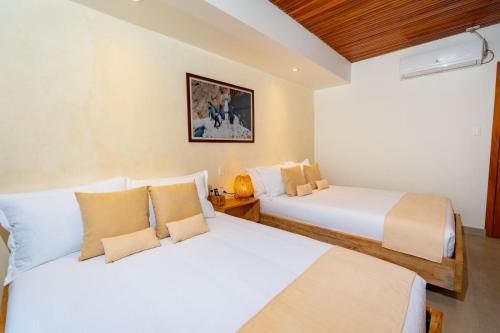two beds in a hotel room with white sheets at El Barranco Galapagos in Puerto Ayora