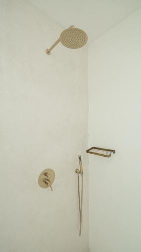 a white wall with a shower head and a tool at Pagi Villas by Betterplace in Canggu