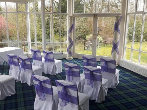 a room with purple and white chairs and windows at Kirkconnel Hall Hotel in Ecclefechan