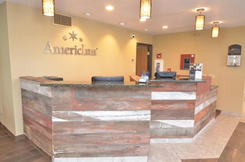 a lobby area with a counter, chairs, and a clock on the wall at AmericInn by Wyndham Mount Pleasant in Mount Pleasant