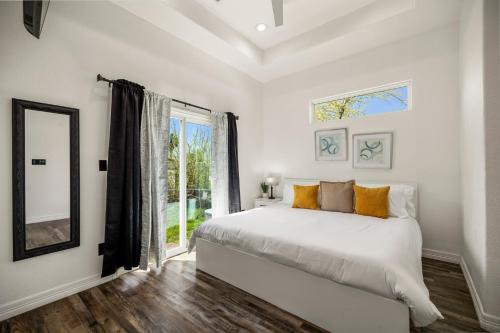 a white bedroom with a bed and a large window at Modern and Serene Oasis Mins from Downtown Houston in Houston