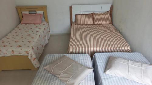 three twin beds in a room with a bed and a pillow at Casa - Aluguel por temporada in Garanhuns