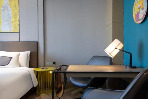 a hotel room with a bed and a desk with a lamp at MiniMax Premier Hotel Shanghai Hongqiao in Shanghai