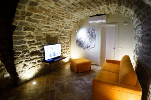 a living room with a couch and a tv in a stone wall at Umbria nel cuore in Cannara