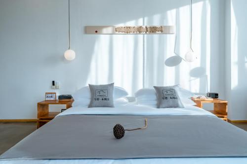 a white bedroom with a large white bed with two pillows at Dali Kong Xiang Weiwenshan Craft hotel in Dali
